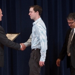 Doctor Potteiger shaking hands with an award recipient in a blue striped shirt